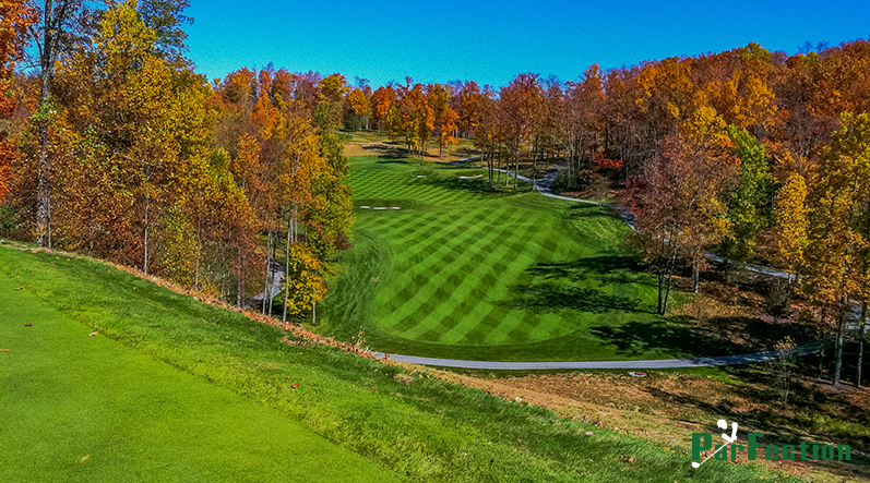 Image shows a beautiful golf green surrounded by trees with autumn-colored leaves.
