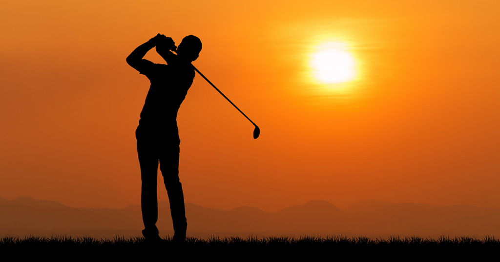 Silhouette of golfer follow-through at sunset on a quiet course