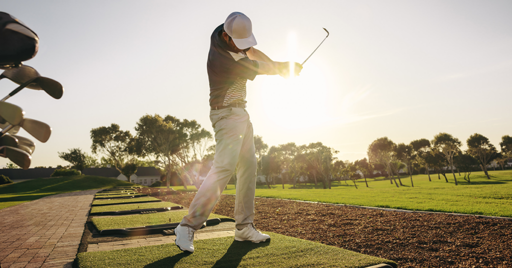 Golfer follow-through showing knee position in the golf swing at sunrise on the driving range